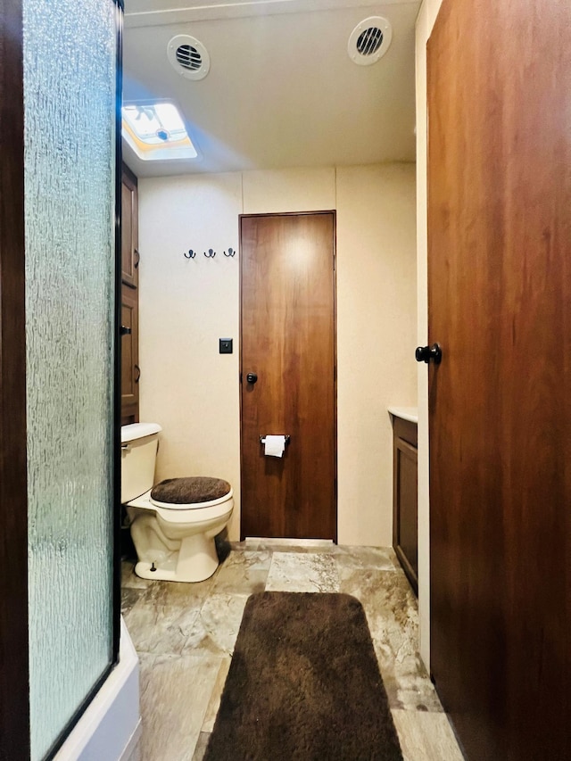 bathroom featuring toilet, vanity, and visible vents