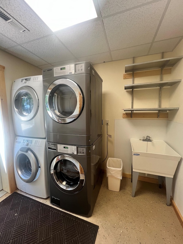clothes washing area with laundry area, stacked washer and clothes dryer, baseboards, and visible vents