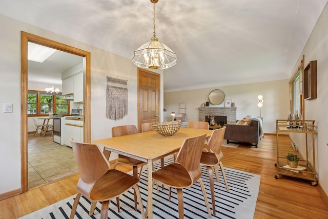 9017 31st St, Saint Louis Park, MN 55426 - dining area featuring a chandelier, a stone fireplace, and light wood-style flooring