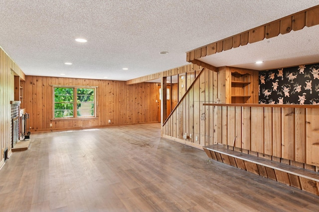 9017 31st St, Saint Louis Park, MN 55426 - unfurnished living room with a textured ceiling, wood finished floors, stairs, recessed lighting, and wood walls