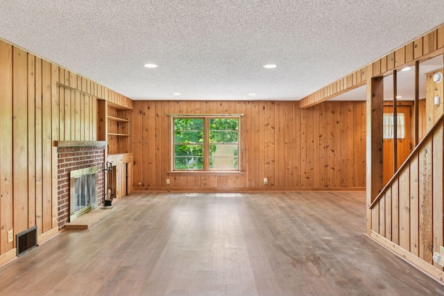 9017 31st St, Saint Louis Park, MN 55426 - unfurnished living room with a fireplace, wood finished floors, recessed lighting, wood walls, and a textured ceiling