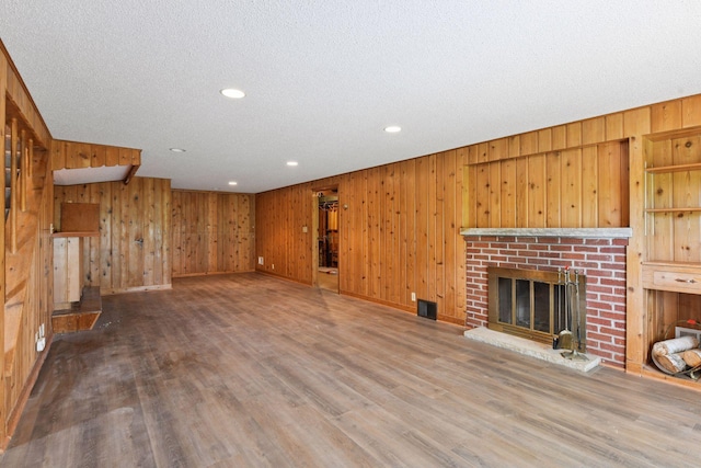 9017 31st St, Saint Louis Park, MN 55426 - unfurnished living room with wood walls, recessed lighting, a brick fireplace, wood finished floors, and a textured ceiling