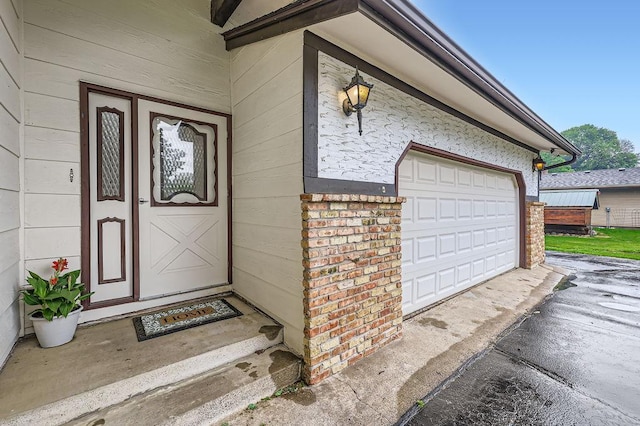 211 Mckinley St, Anoka, MN 55303 - view of exterior entry with a garage, brick siding, and asphalt driveway