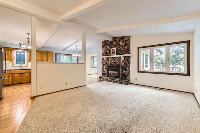 211 Mckinley St, Anoka, MN 55303 - unfurnished living room featuring a stone fireplace, a chandelier, light wood-style flooring, baseboards, and a sink