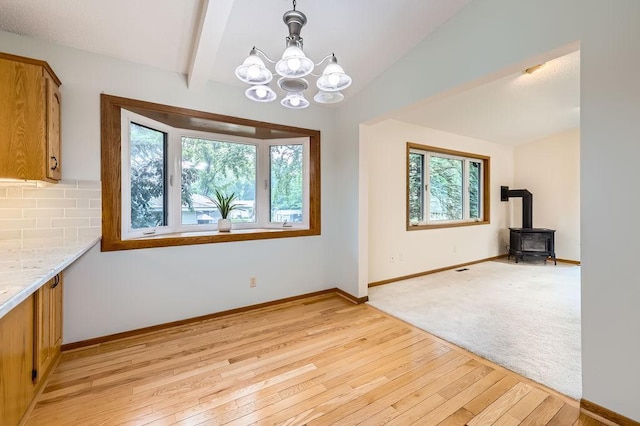 211 Mckinley St, Anoka, MN 55303 - unfurnished dining area with a chandelier, light wood finished floors, a wood stove, and baseboards