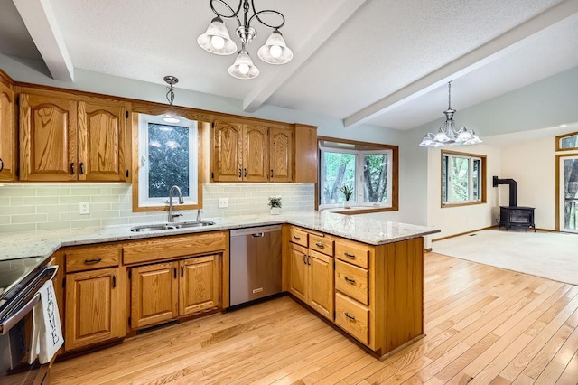 211 Mckinley St, Anoka, MN 55303 - kitchen with stainless steel appliances, a sink, a chandelier, a wood stove, and a peninsula