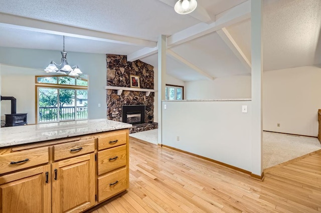 211 Mckinley St, Anoka, MN 55303 - kitchen with a wood stove, light wood-type flooring, light stone countertops, hanging light fixtures, and baseboards