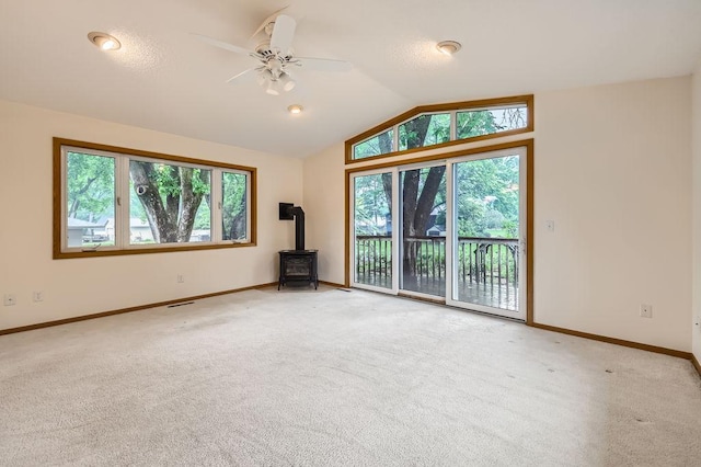 211 Mckinley St, Anoka, MN 55303 - unfurnished room featuring vaulted ceiling, healthy amount of natural light, a wood stove, and light carpet