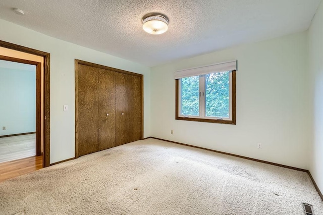 211 Mckinley St, Anoka, MN 55303 - unfurnished bedroom featuring a closet, carpet flooring, baseboards, and a textured ceiling