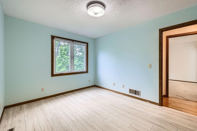 211 Mckinley St, Anoka, MN 55303 - empty room featuring a textured ceiling, light wood-style flooring, and baseboards
