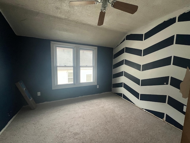 carpeted spare room with a textured ceiling, ceiling fan, and baseboards