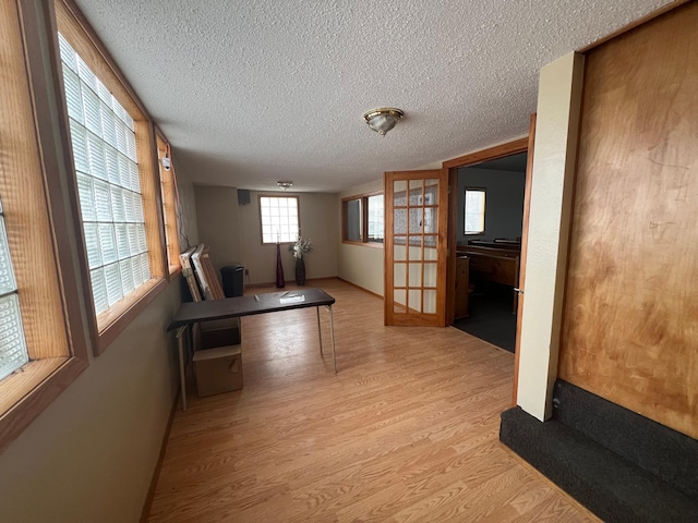 hall featuring light wood-style flooring and a textured ceiling