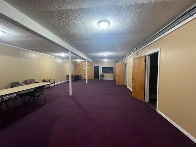 finished basement featuring a textured ceiling, baseboards, and carpet