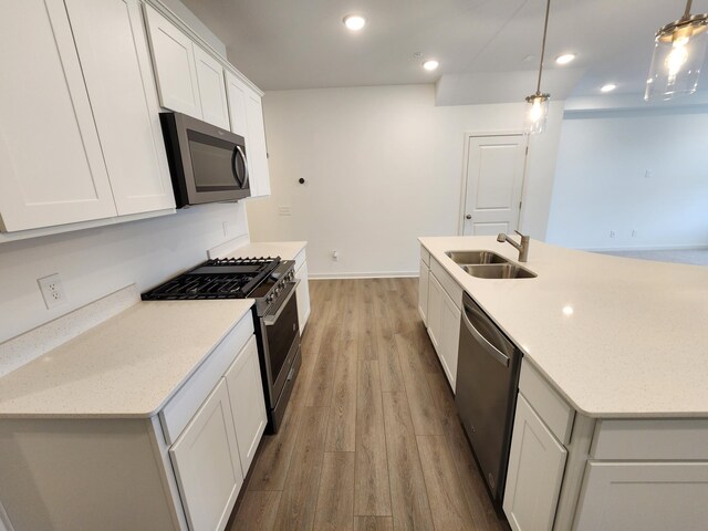kitchen featuring white cabinets, a sink, light wood-type flooring, appliances with stainless steel finishes, and recessed lighting