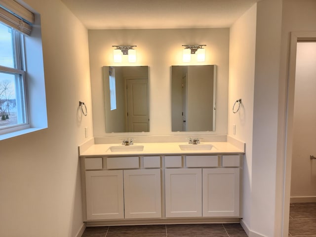 bathroom featuring double vanity, a sink, and baseboards