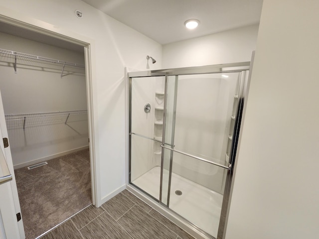 bathroom with a shower stall, a walk in closet, and visible vents
