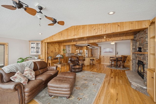 1867 Beach Dr SE, Forest Lake, MN 55025 - living area with wood walls, vaulted ceiling, ceiling fan, light wood finished floors, and a fireplace