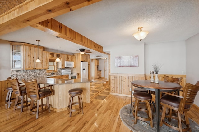 1867 Beach Dr SE, Forest Lake, MN 55025 - dining room featuring light wood finished floors, a wainscoted wall, wood walls, ceiling fan, and beam ceiling