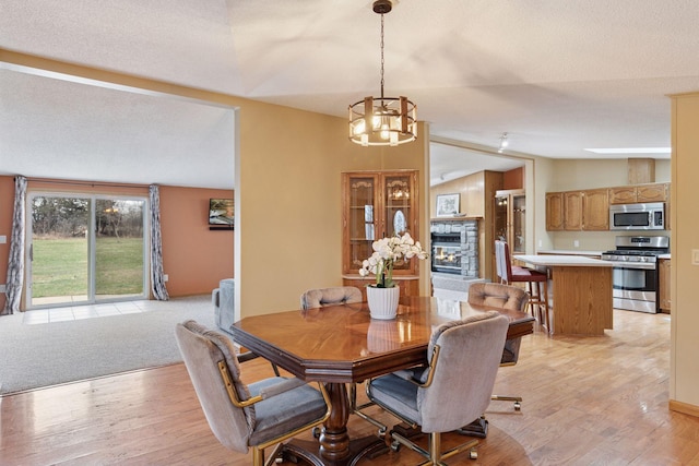 34115 Malmberg Ave, Chisago Lake Twp, MN 55045 - dining area with a fireplace, light wood-type flooring, and a chandelier