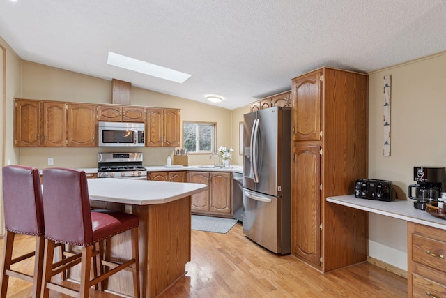 34115 Malmberg Ave, Chisago Lake Twp, MN 55045 - kitchen featuring appliances with stainless steel finishes, a skylight, brown cabinetry, lofted ceiling, and a textured ceiling