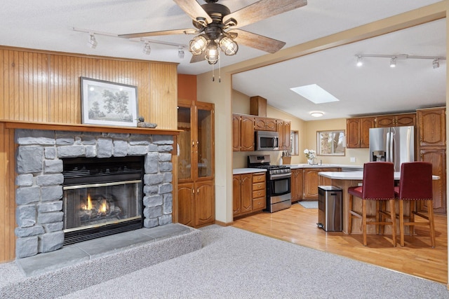 34115 Malmberg Ave, Chisago Lake Twp, MN 55045 - kitchen featuring appliances with stainless steel finishes, rail lighting, brown cabinets, light countertops, and a skylight