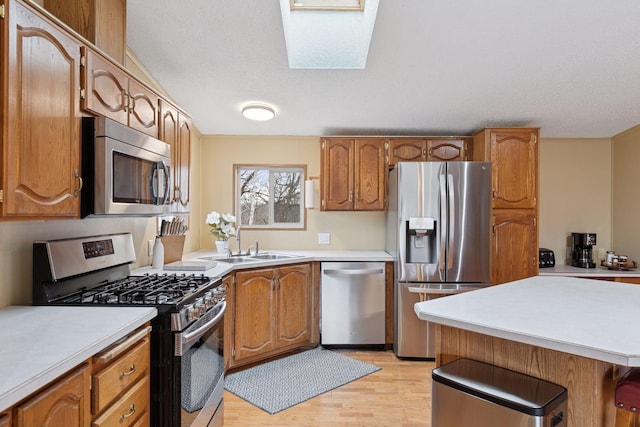 34115 Malmberg Ave, Chisago Lake Twp, MN 55045 - kitchen featuring appliances with stainless steel finishes, a skylight, light countertops, light wood-type flooring, and brown cabinetry