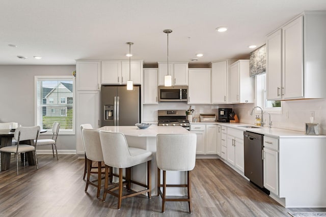 9444 Bridle Way, Victoria, MN 55386 - kitchen with appliances with stainless steel finishes, a sink, wood finished floors, a breakfast bar, and white cabinetry