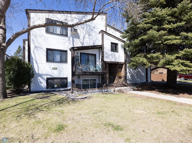 view of front of home featuring stucco siding, a balcony, and a front yard