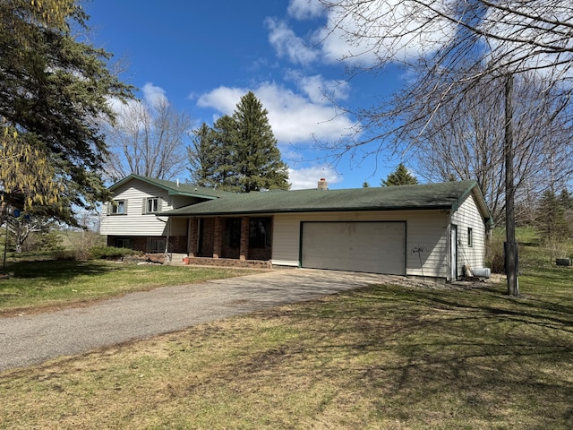 tri-level home featuring a garage, driveway, a front yard, and a chimney