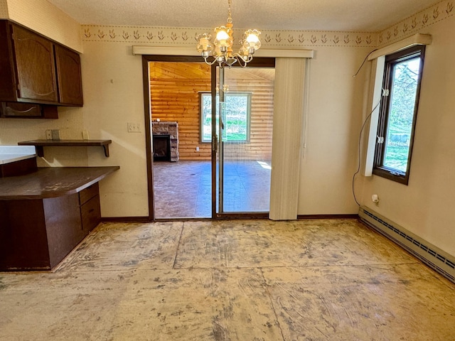 unfurnished dining area with a chandelier, plenty of natural light, a baseboard radiator, and a stone fireplace