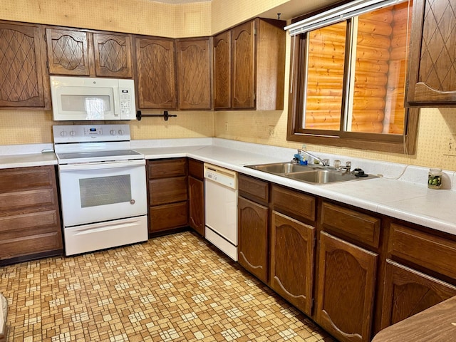 kitchen featuring white appliances, a sink, light countertops, and light flooring