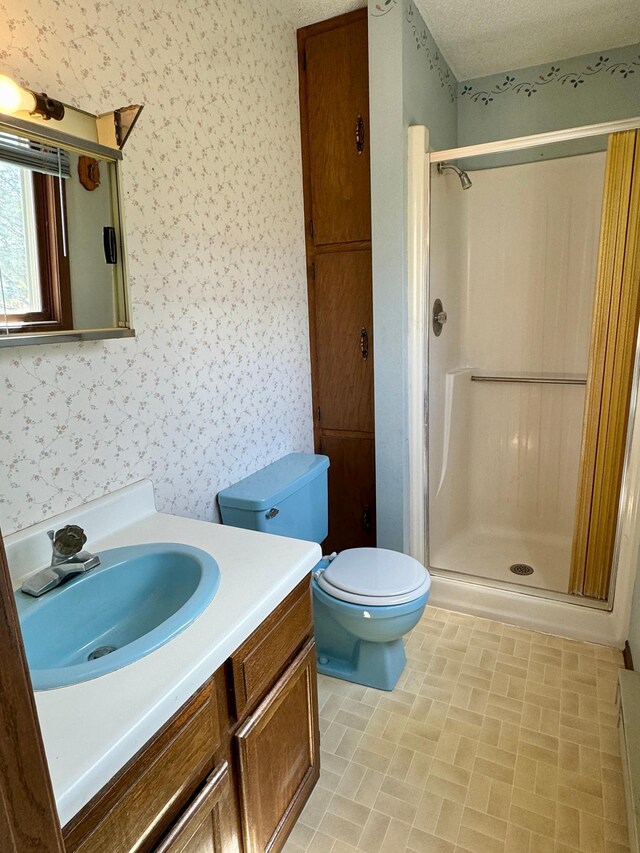 full bathroom featuring wallpapered walls, a shower stall, vanity, and toilet