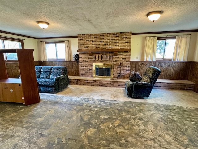 living room with a textured ceiling, a wainscoted wall, crown molding, wood walls, and a brick fireplace