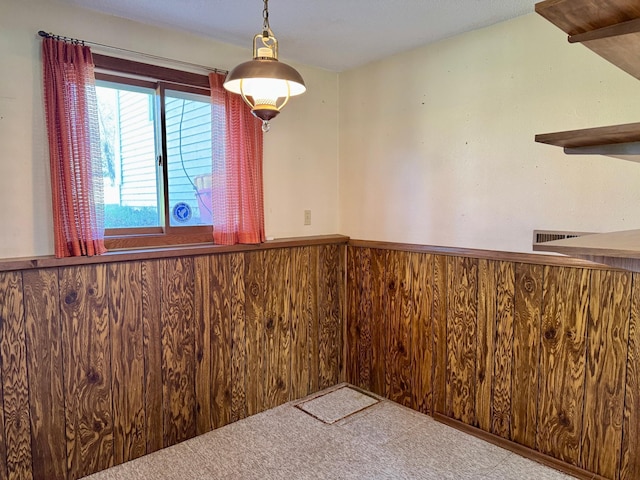 unfurnished dining area with wainscoting, carpet, and wooden walls