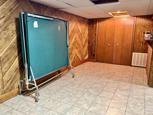 finished below grade area with wood walls, baseboards, and a drop ceiling