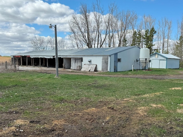 rear view of house featuring an outbuilding, a yard, metal roof, and an outdoor structure