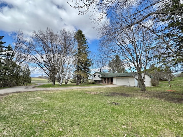 view of grassy yard with a garage and driveway