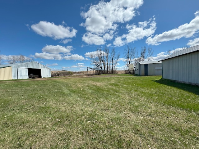 view of green lawn featuring a pole building, an outdoor structure, and a detached garage