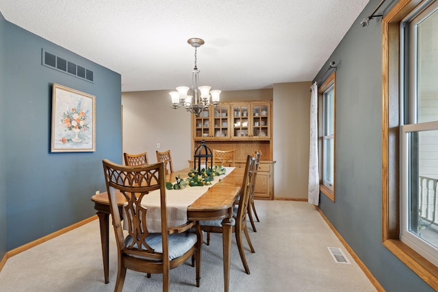 dining room with visible vents, baseboards, a chandelier, and light carpet