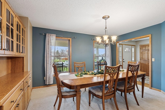 dining area featuring light colored carpet, a textured ceiling, a chandelier, and baseboards