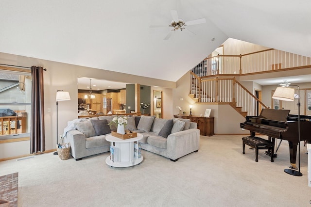 living area featuring stairway, a ceiling fan, high vaulted ceiling, and light carpet