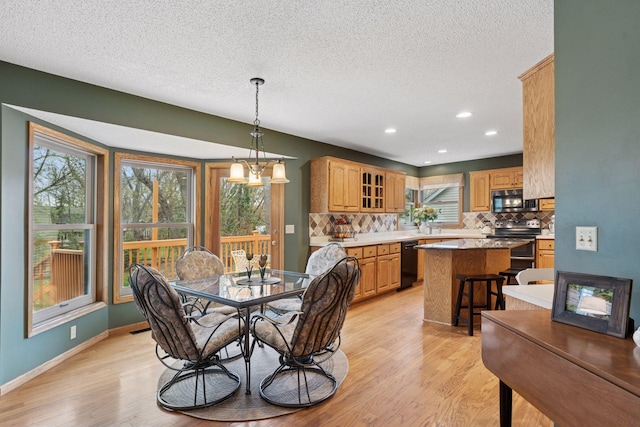 dining space with a textured ceiling, light wood-style floors, and plenty of natural light