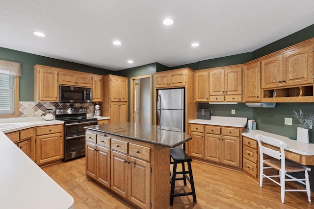 kitchen featuring light wood finished floors, a center island, backsplash, double oven range, and freestanding refrigerator