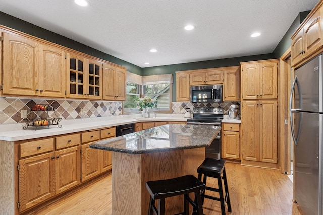 kitchen with light wood-style flooring, a sink, stainless steel appliances, a center island, and a kitchen bar