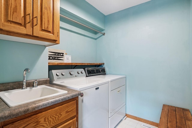 laundry room with a sink, baseboards, cabinet space, and washer and clothes dryer
