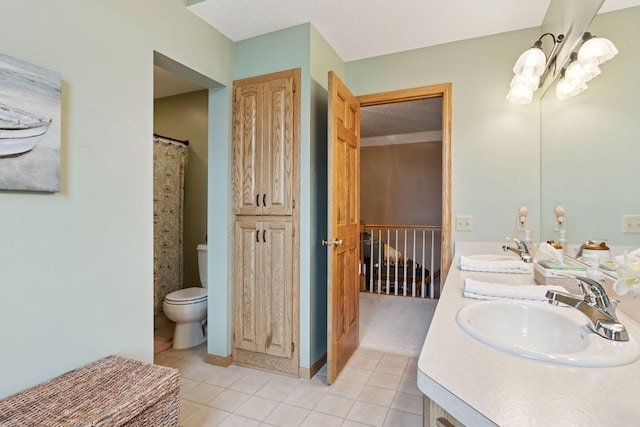 bathroom featuring toilet, double vanity, a sink, and tile patterned floors