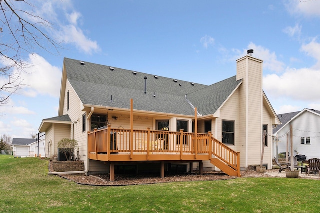 back of house featuring a deck, roof with shingles, a chimney, and a lawn