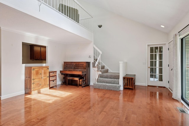 living area featuring stairs, light wood-type flooring, high vaulted ceiling, baseboards, and recessed lighting