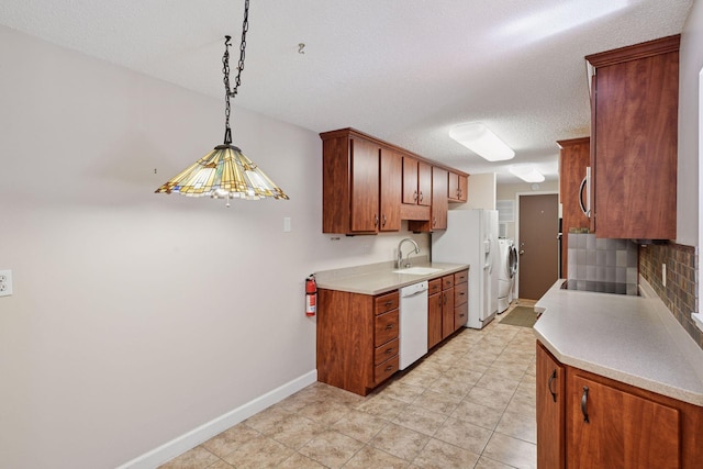 kitchen with washer and clothes dryer, white appliances, a sink, backsplash, and light countertops
