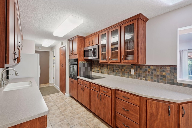 kitchen featuring a sink, black appliances, a textured ceiling, and light countertops